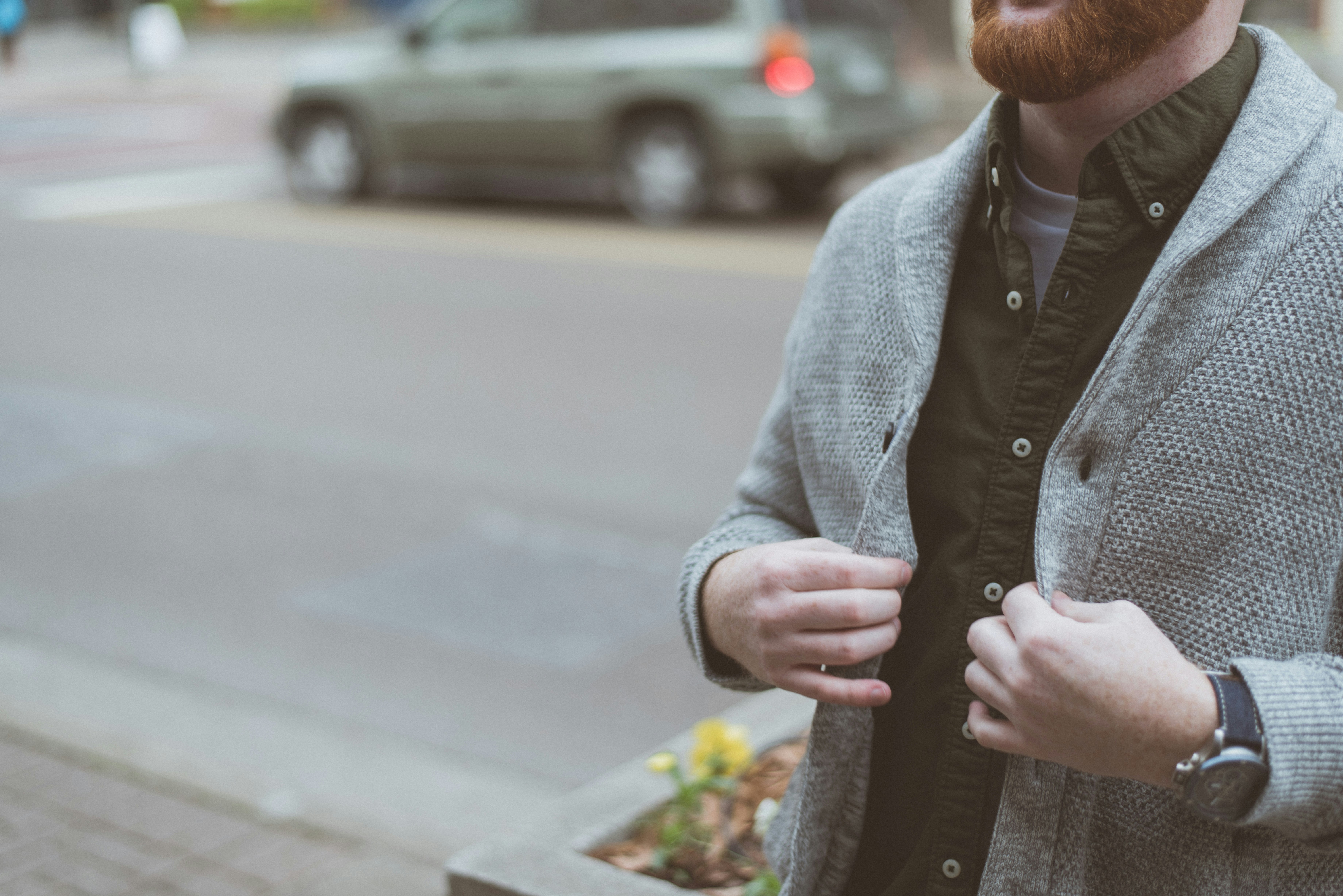 man holding his gray cardigan